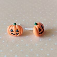 Load image into Gallery viewer, A pair of flat backed jack o' lantern earrings with relief sculpted detail and painted on face and stem. The earrings are sitting on a orange and white polka dot background.