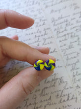 Load image into Gallery viewer, Yellow, blue, and purple swirl earrings held between finger and thumb

